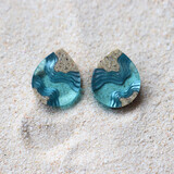 Light blue stud earrings on sand