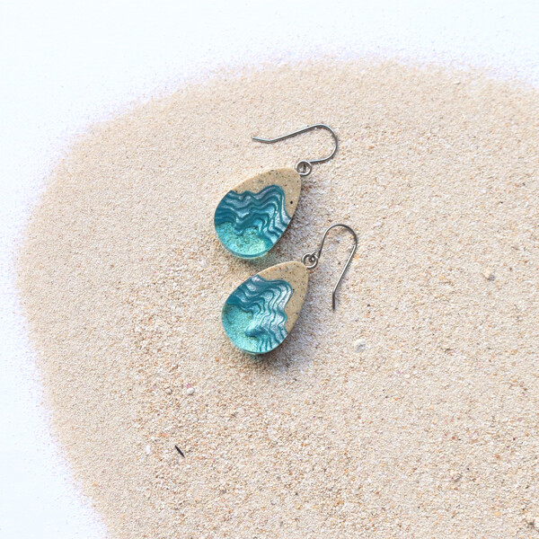 Light blue dangle earrings on sand